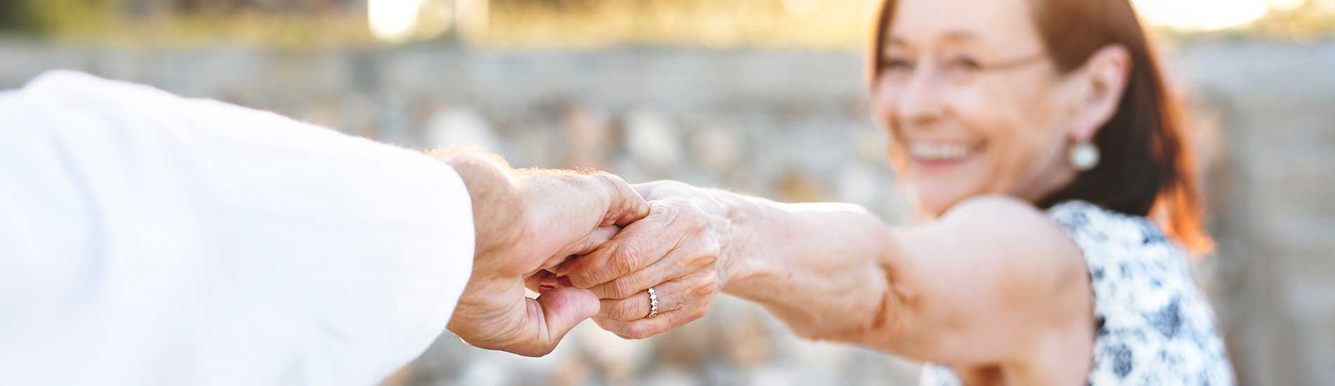 elderly woman holding husband's hand