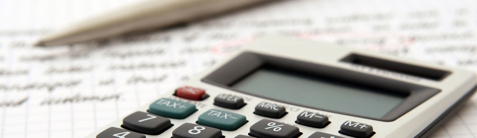 close-up of calculator and pen on graph paper