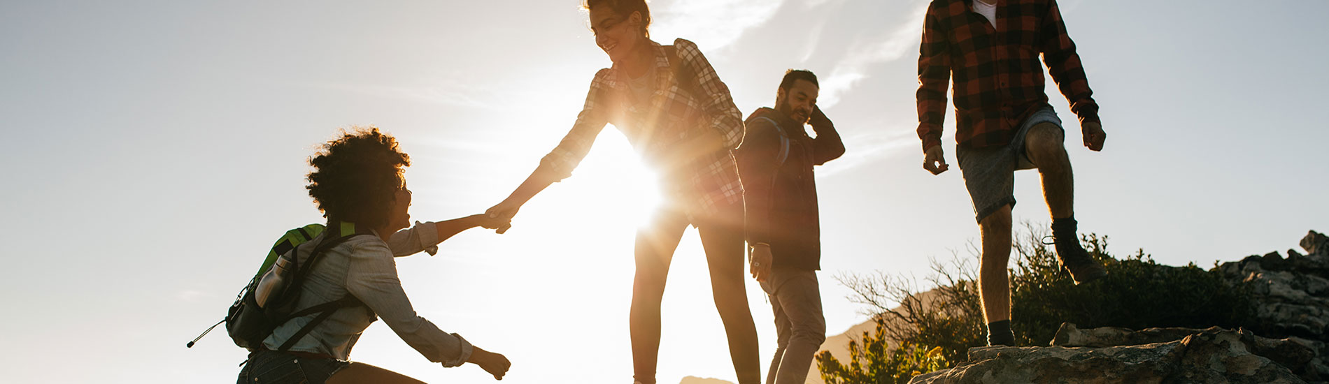 group of people on a hike with one woman helping another woman