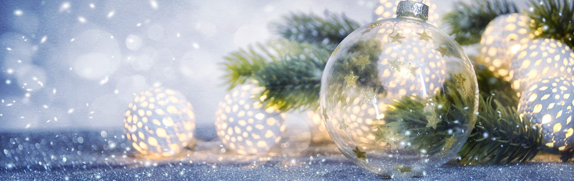 Clear Christmas ornaments amongst evergreen and christmas lights